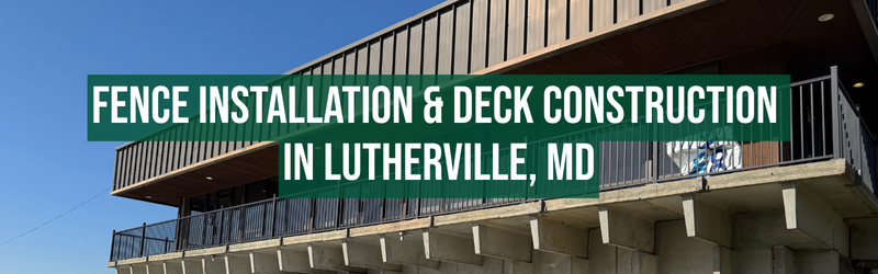 A building with a balcony featuring a black railing, under a clear blue sky. A green banner with white text reads: "FENCE INSTALLATION & DECK CONSTRUCTION IN LUTHERVILLE, MD." The building has a modern design with a brown and black exterior.