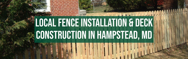 The image shows a wooden picket fence running along a grassy area in front of a residential house. There is a large green banner with white text overlaid on the image that reads: "LOCAL FENCE INSTALLATION & DECK CONSTRUCTION IN HAMPSTEAD, MD." The background includes a brick house, some trees, and a chain-link fence.