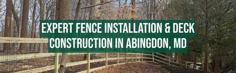 Wood split rail fence with wire mesh running through a wooded residential area with leaf-covered ground and tall trees. Overlaid text reads: “Expert fence installation & deck construction in Abingdon, MD.”