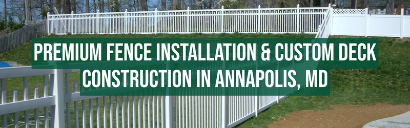A green banner with white text reading "PREMIUM FENCE INSTALLATION & CUSTOM DECK CONSTRUCTION IN ANNAPOLIS, MD," displayed on a white fenced area outdoors, with trees and a grassy hill in the background.
