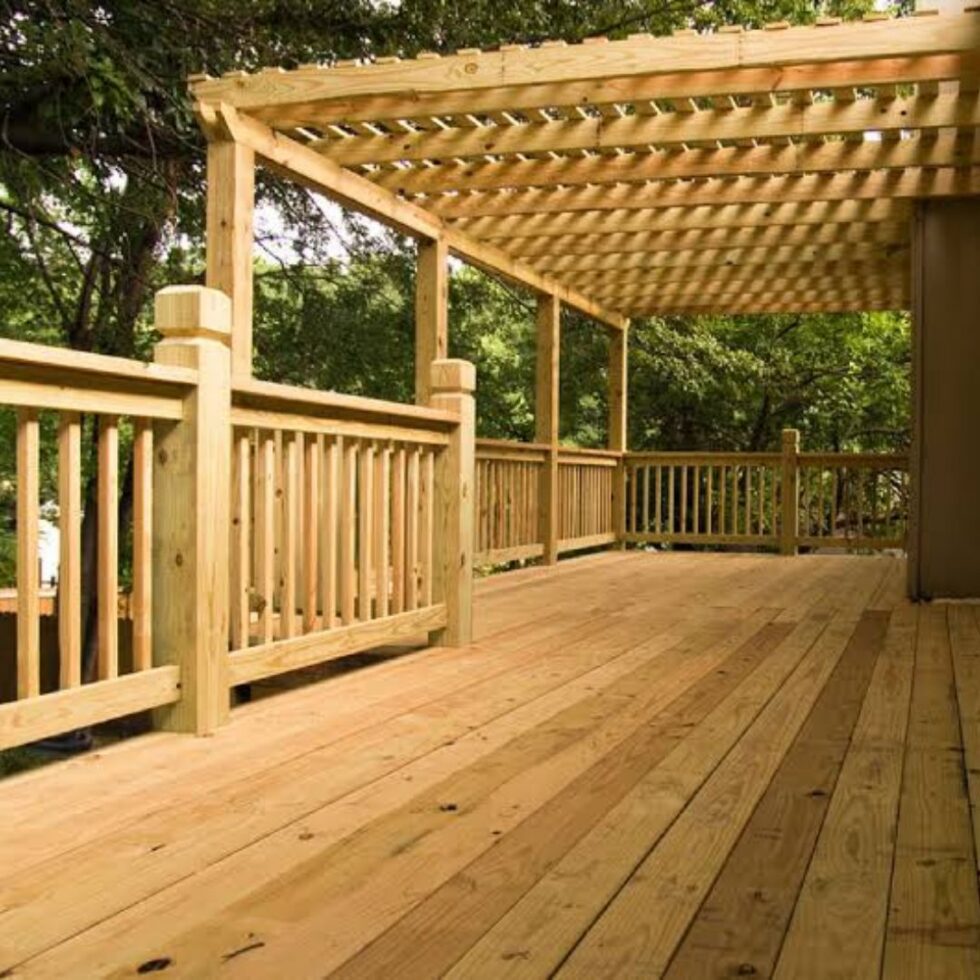 Spacious pressure-treated wood deck with pergola shade structure, safety railings, and an open outdoor living area surrounded by mature trees.